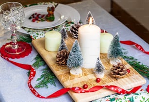un tavolo sormontato da un tagliere di legno ricoperto di pigne e candele