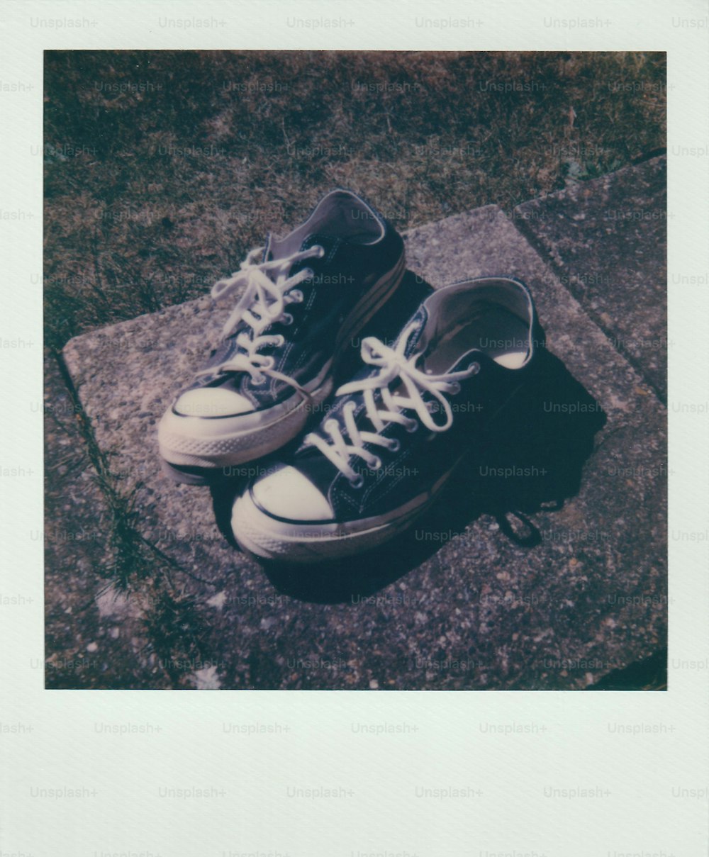 a pair of black and white shoes sitting on top of a sidewalk