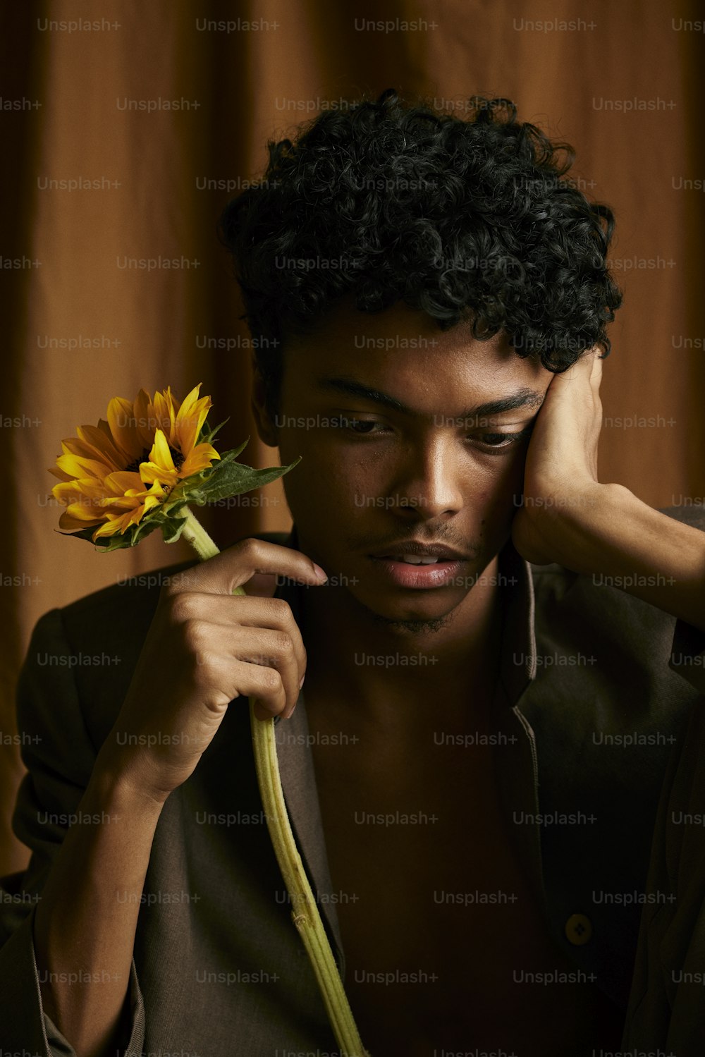 a young man holding a sunflower in his hand