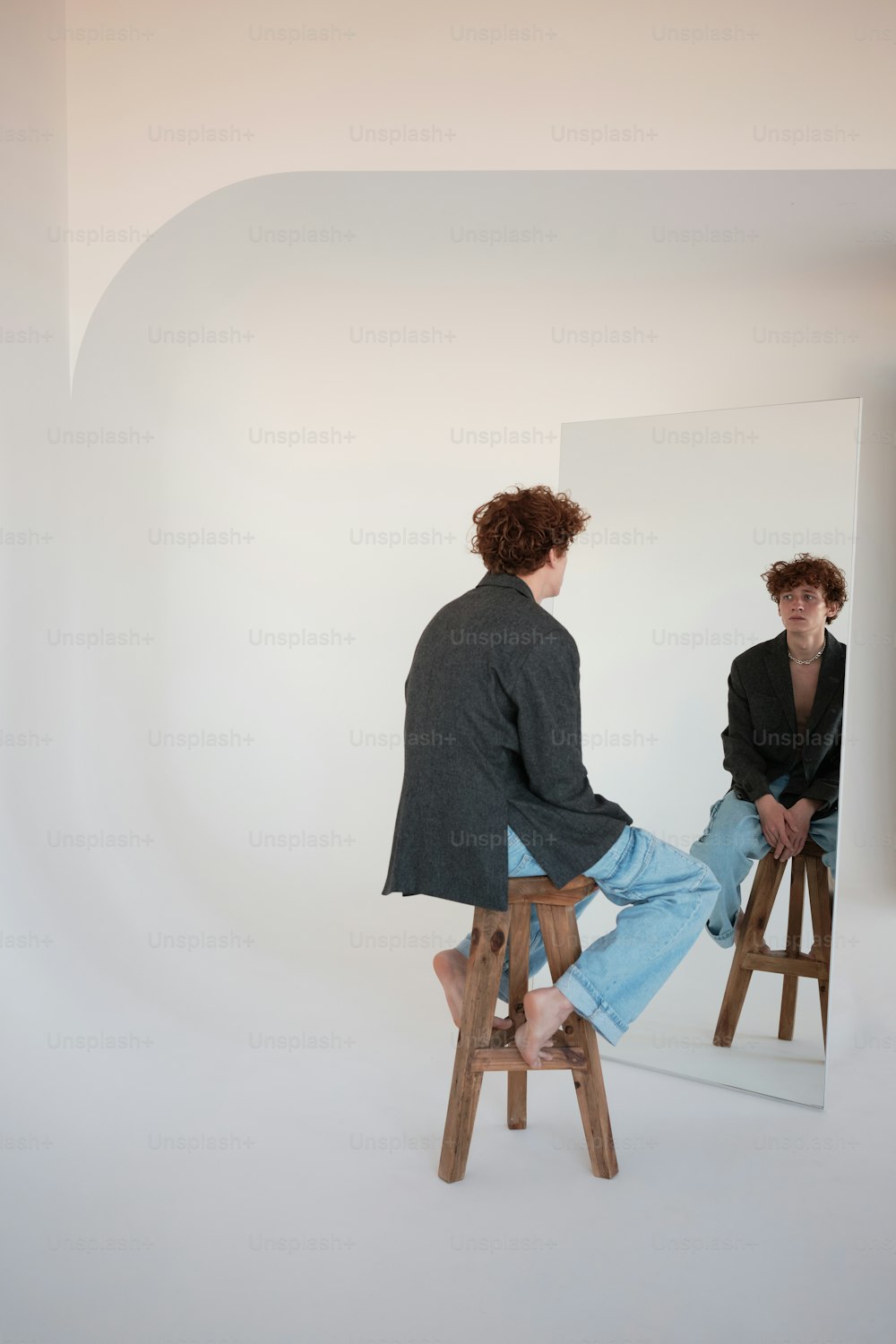 a man sitting on a stool in front of a mirror