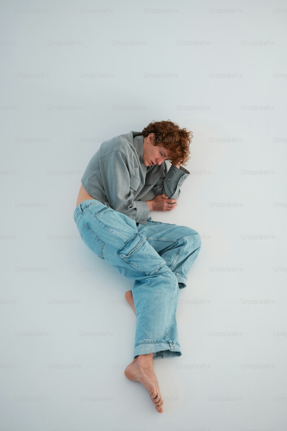 um homem sentado no chão com a cabeça nas mãos