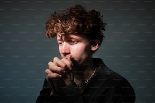 a young man with curly hair is praying