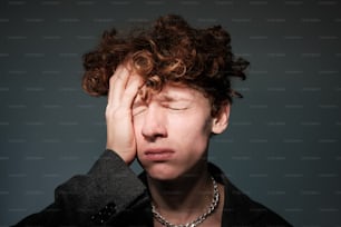 a man with curly hair holding his head