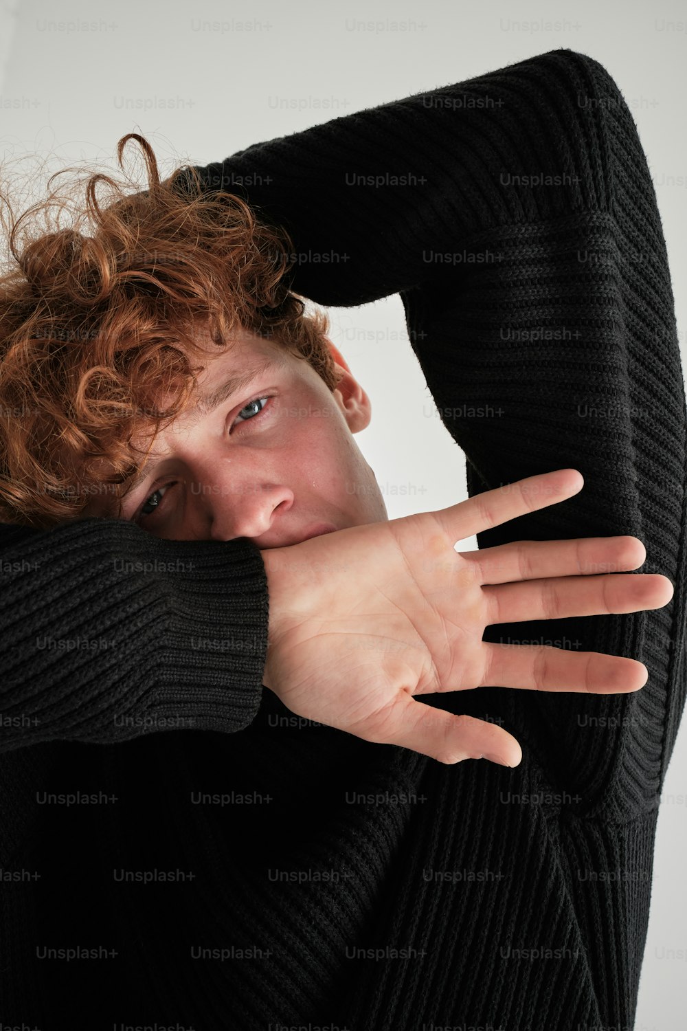 a man with curly hair covering his face with his hands