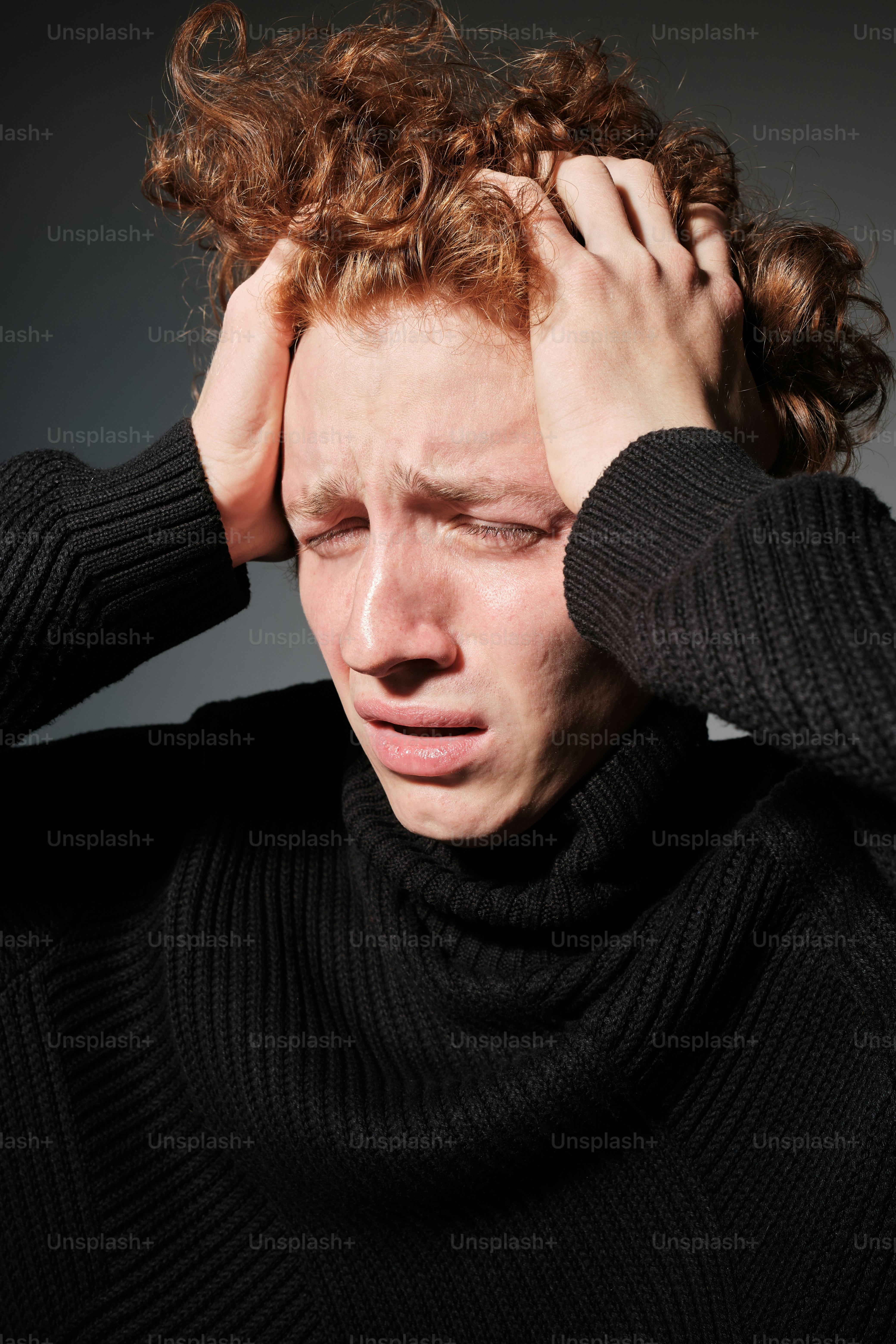 a man with curly hair holding his head
