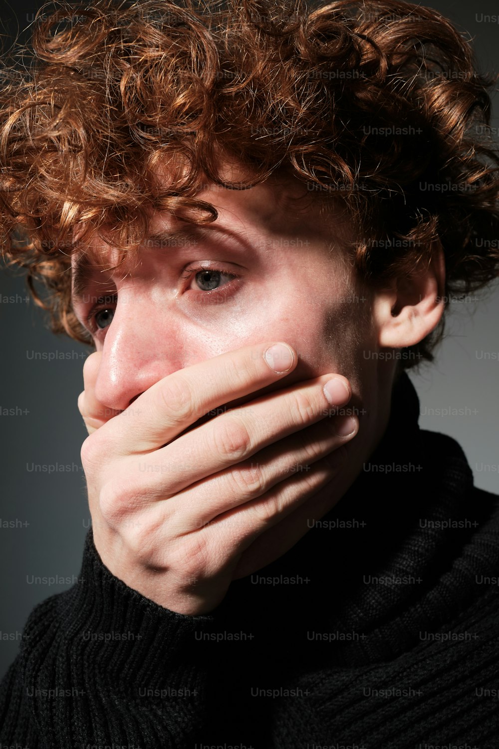a close up of a person covering his mouth