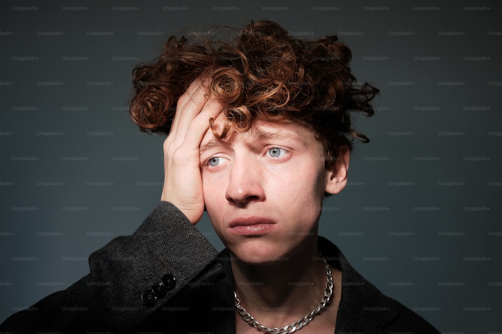 a man with curly hair holding his head