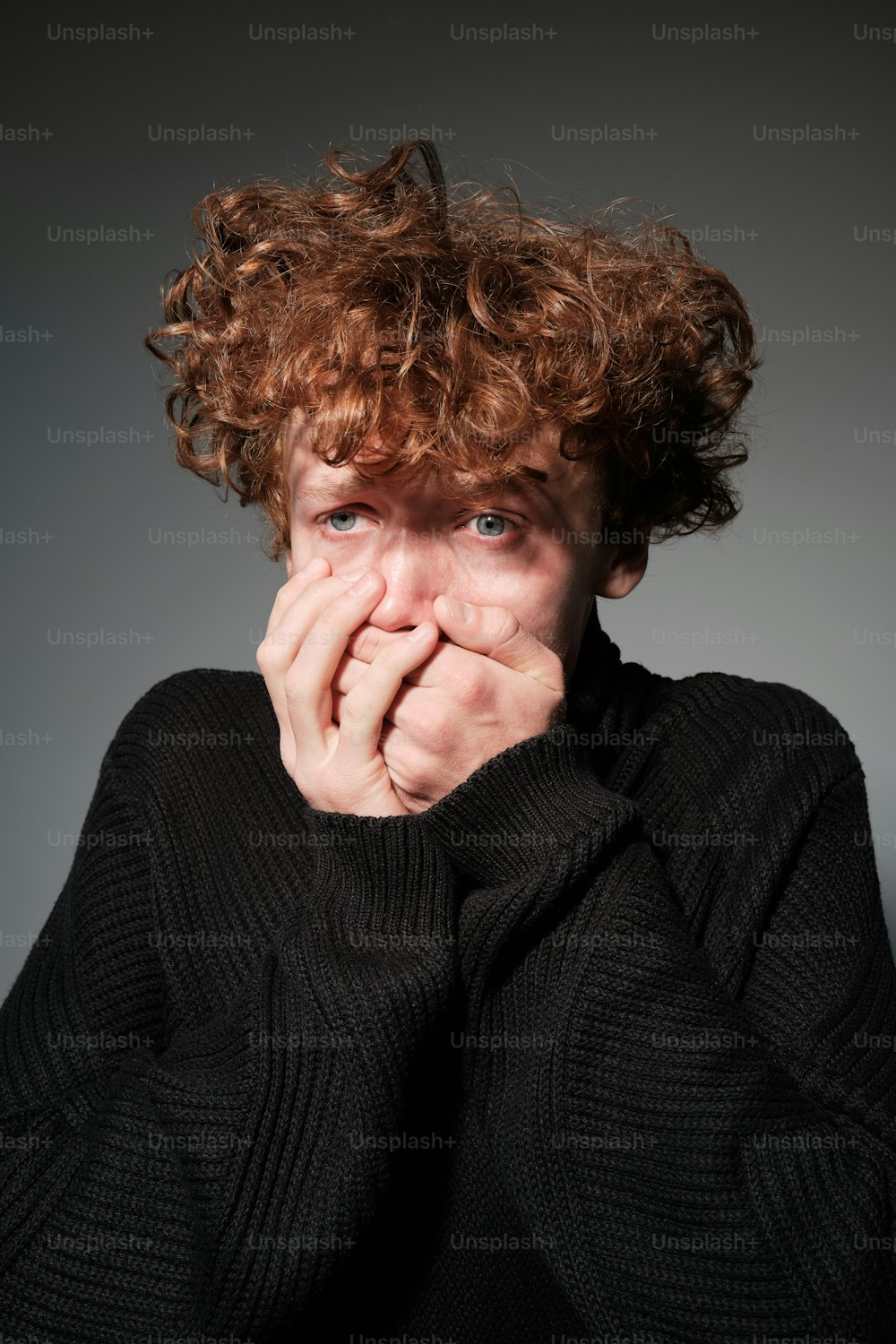 a man with curly hair covering his mouth