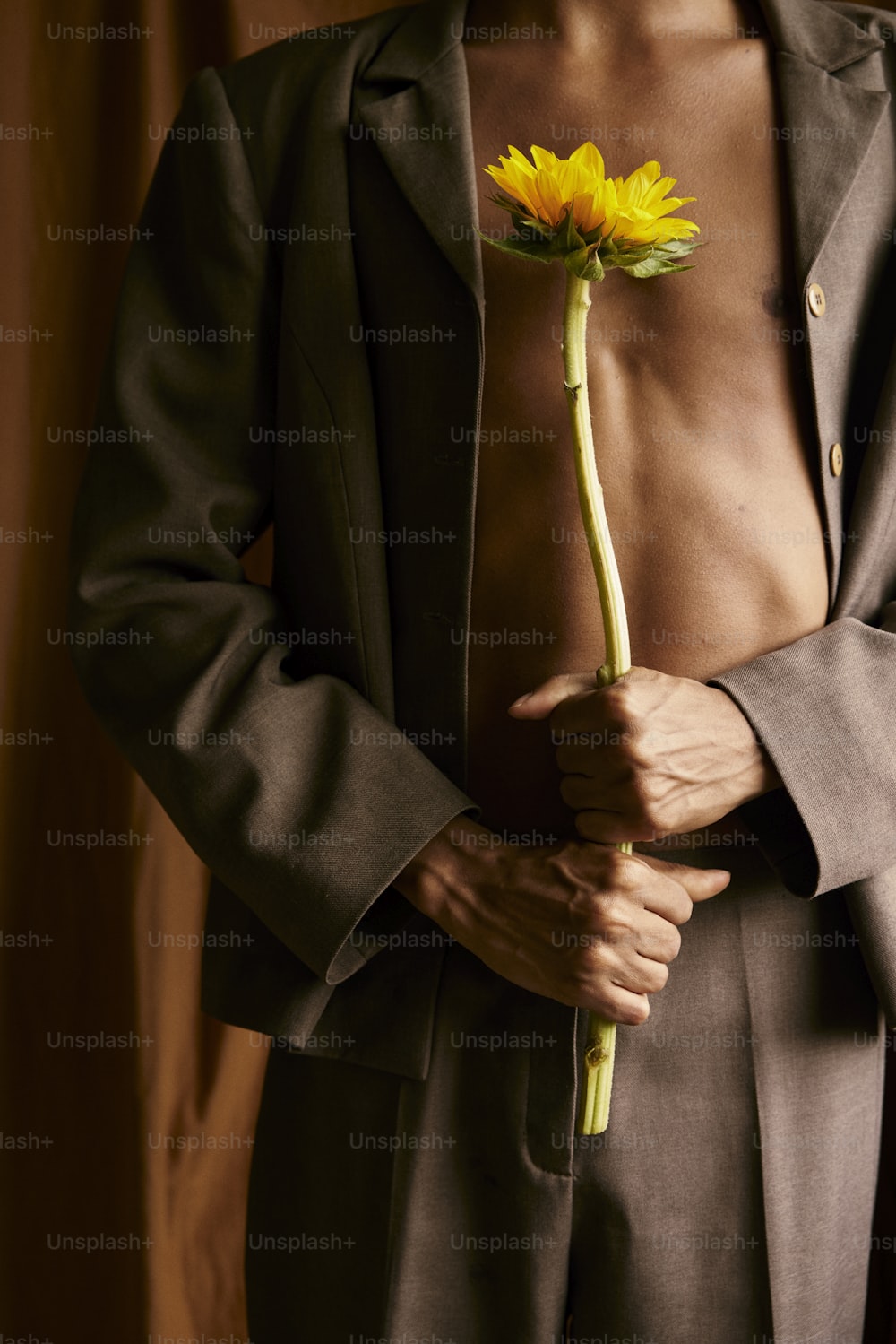 um homem de terno segurando uma flor amarela