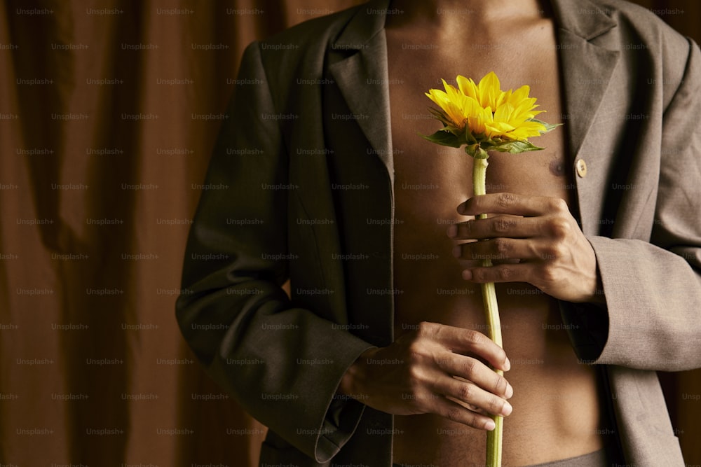 um homem de terno segurando uma flor amarela