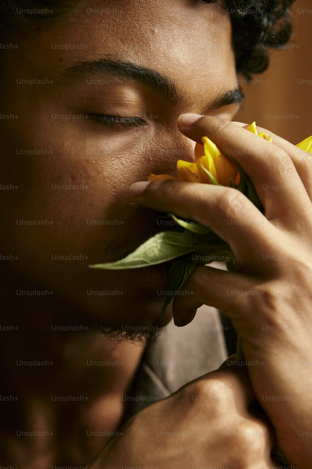 目を閉じて花の匂いを嗅ぐ男