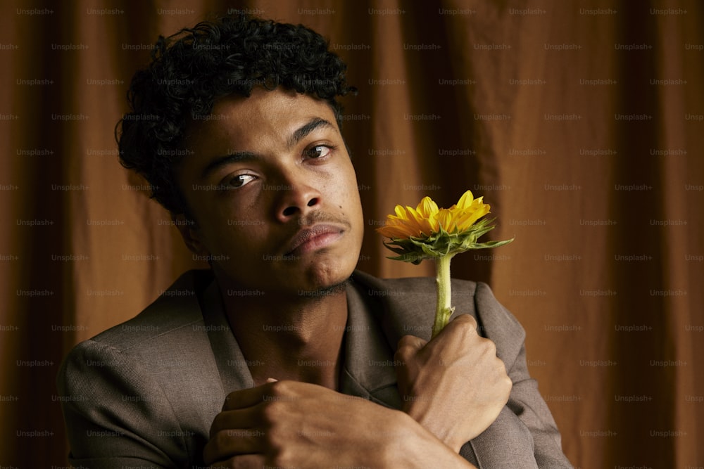 a man holding a flower in front of his face