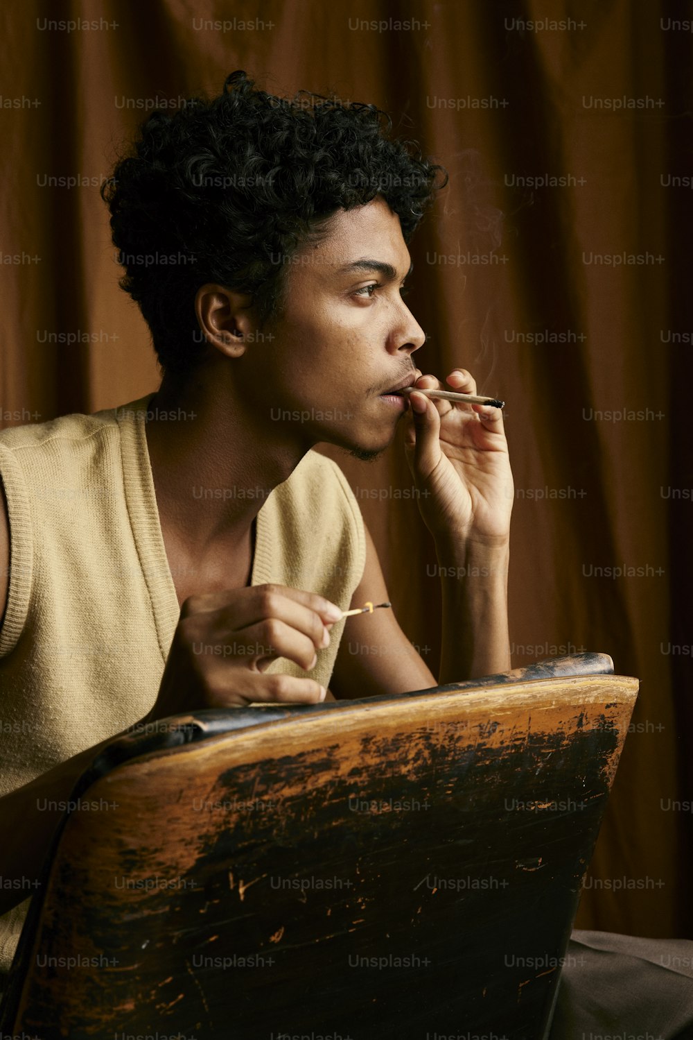 a man smoking a cigarette in front of a wooden box