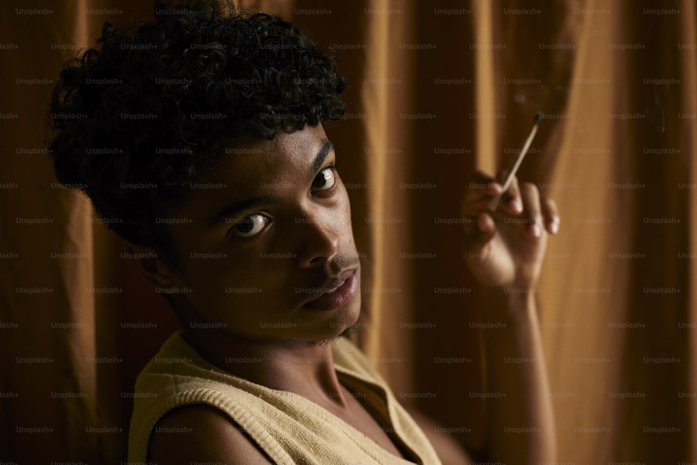 a woman smoking a cigarette in front of a curtain