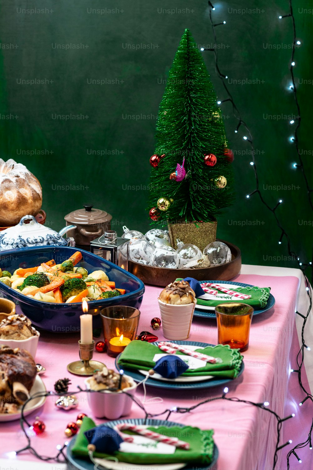 Una mesa cubierta con platos de comida junto a un árbol de Navidad