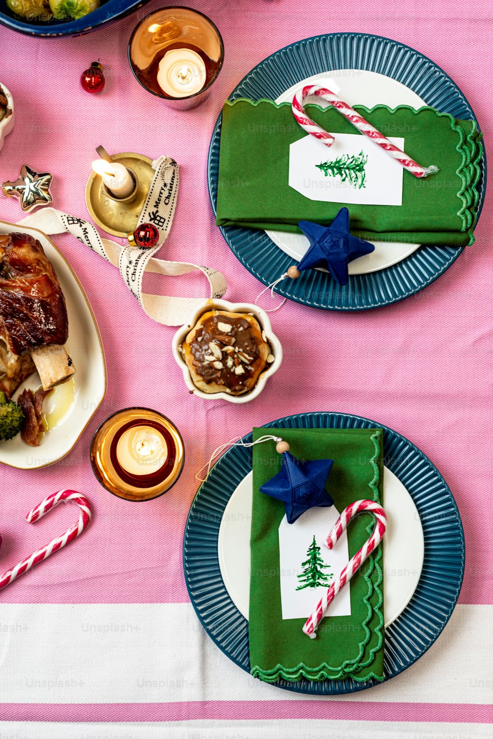 a table set for christmas dinner with place settings and candy canes