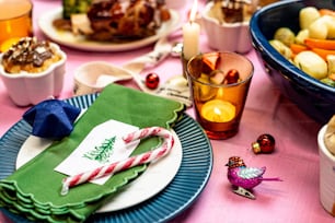 a table set for christmas dinner with plates of food and candy canes