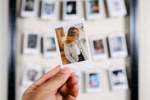 uma mão segurando uma polaroid com uma foto de uma mulher