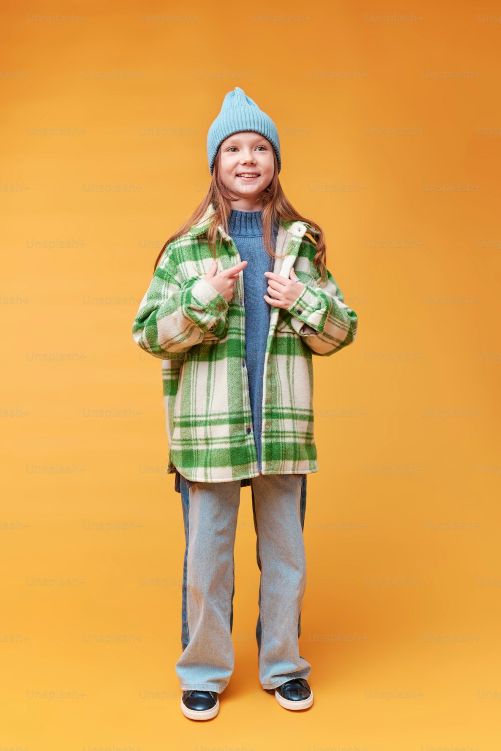 a little girl standing in front of an orange background