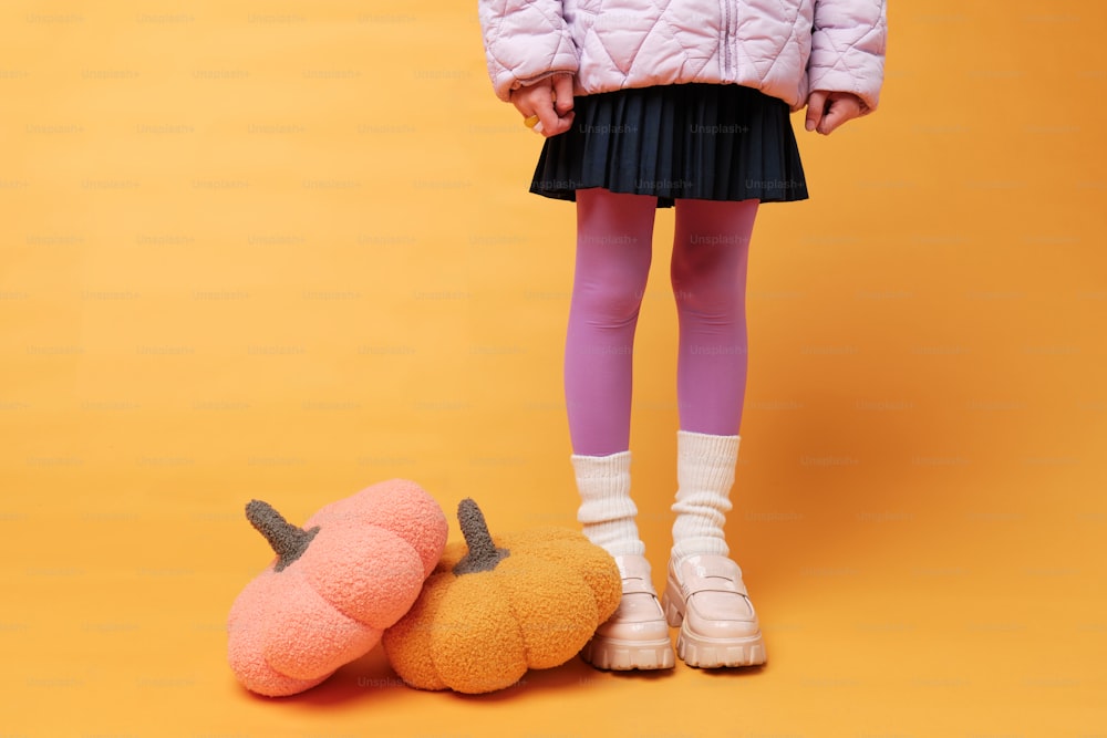 a little girl standing next to a stuffed pumpkin