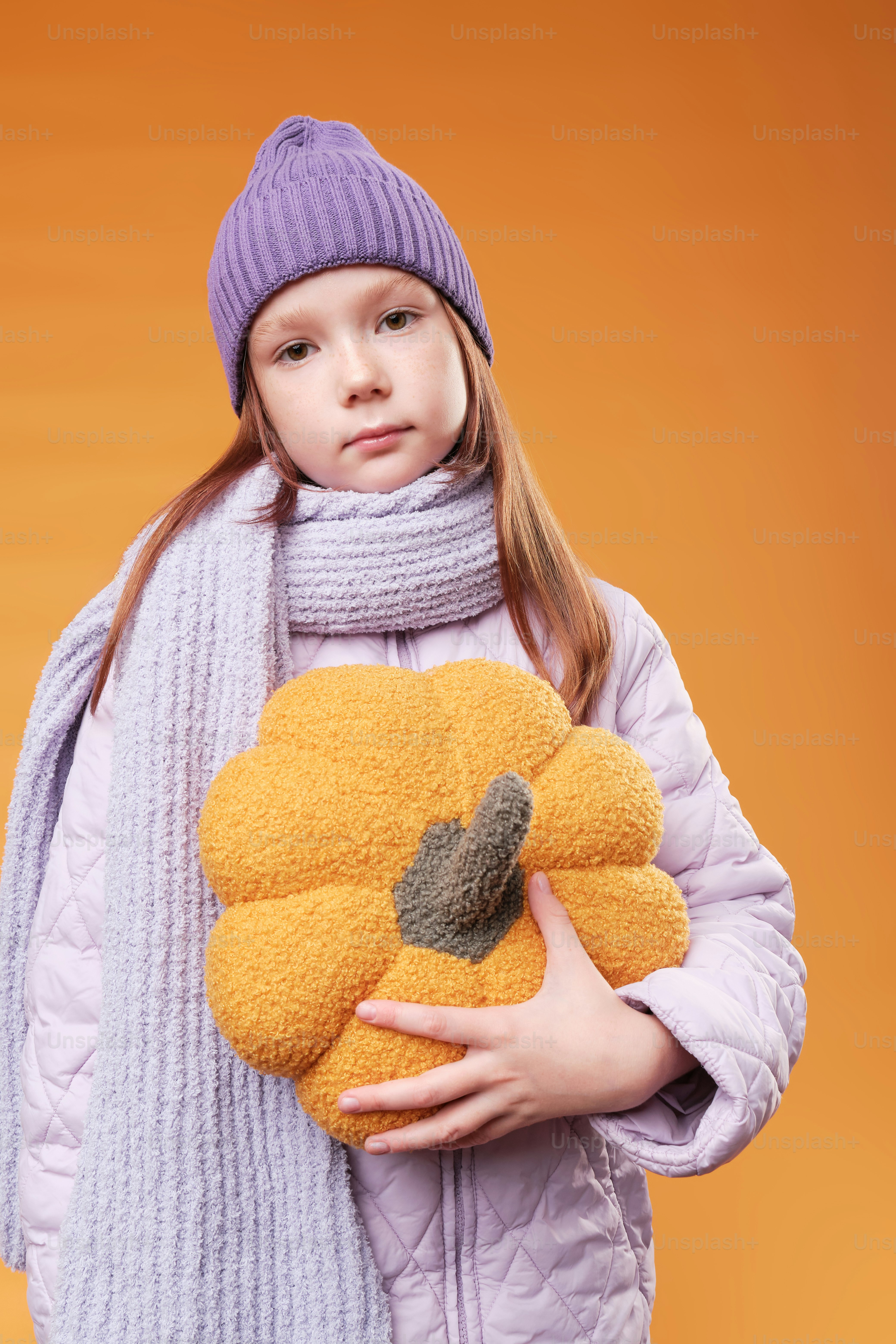 A girl in autumn clothes on studio background in warm color scheme