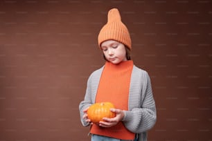a young boy holding a pumpkin in his hands