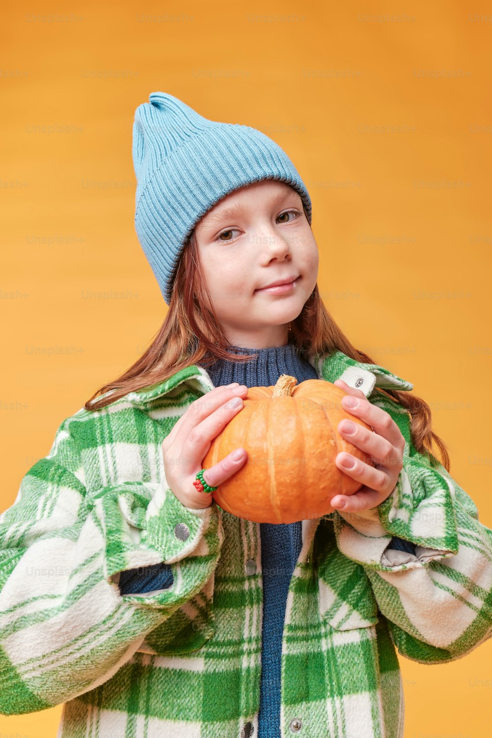 a little girl holding a pumpkin in her hands