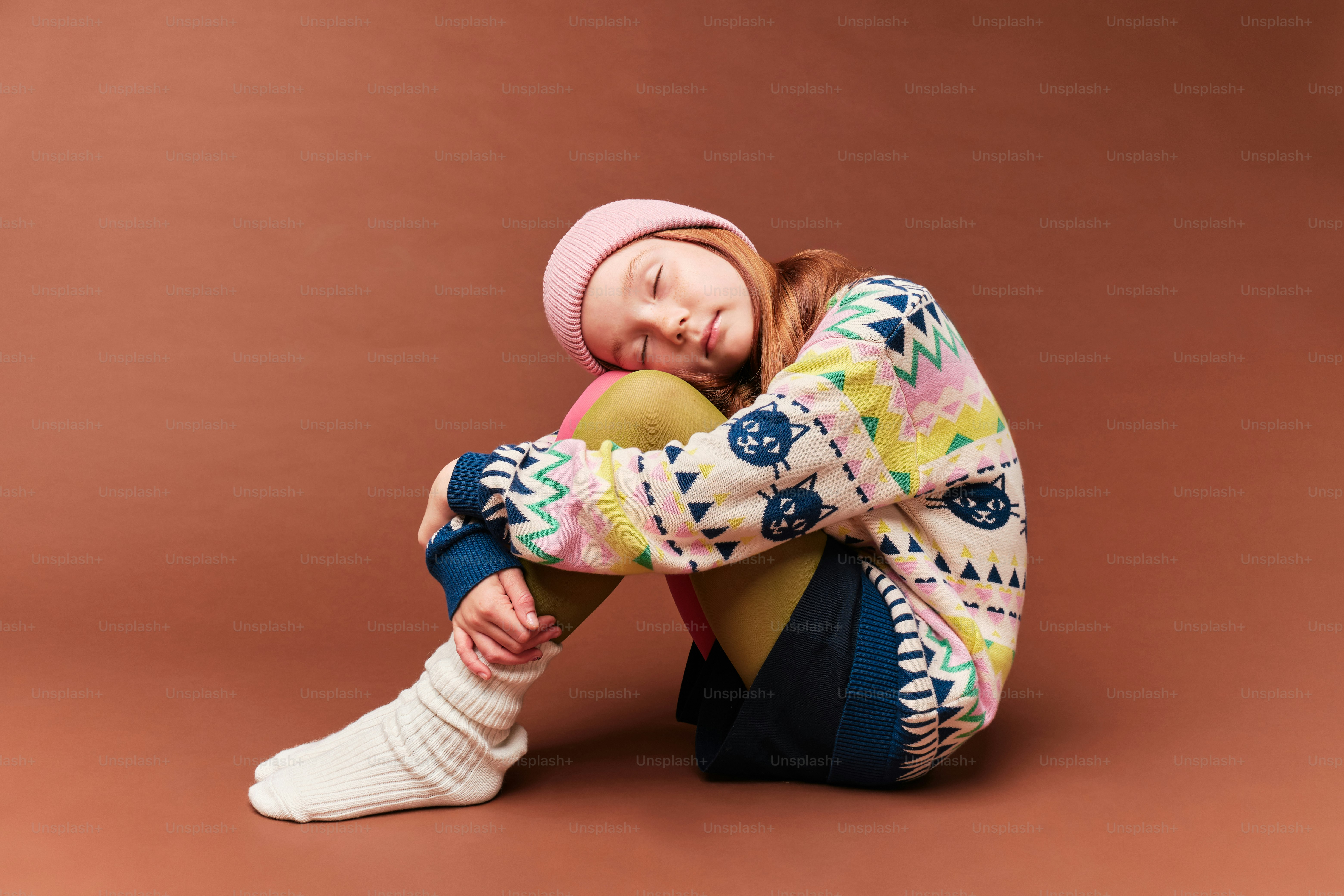 A little girl sitting on the ground with her legs crossed photo – Girl ...
