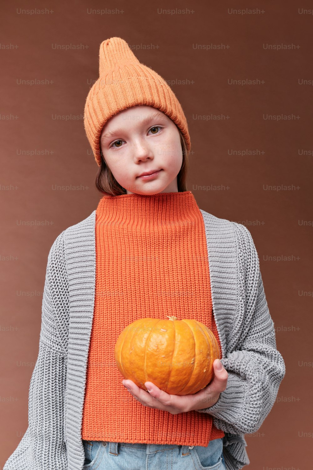 a young girl holding a pumpkin in her hands