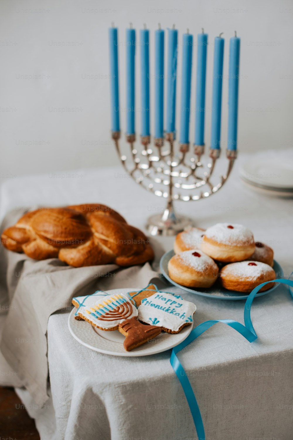 a table topped with a plate of donuts next to a menorah