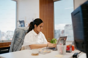 机に座ってノートパソコンで作業する女性