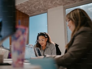 テーブルに座ってノートパソコンで作業する2人の女性