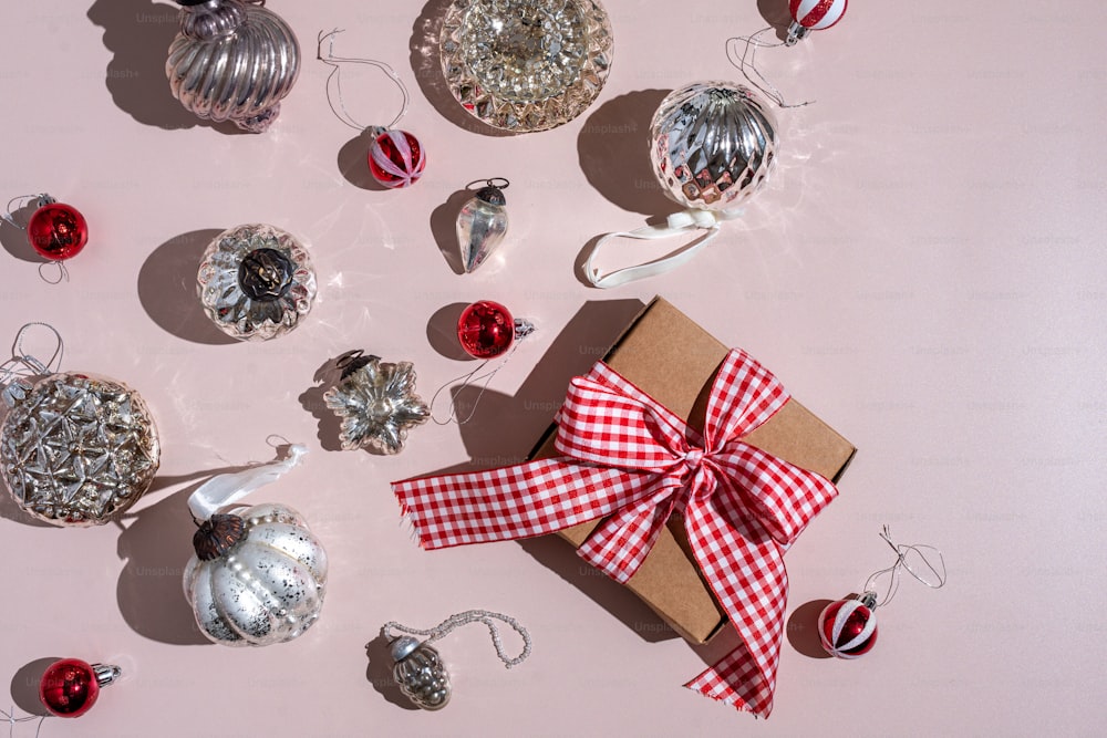 a present wrapped in a red and white checkered ribbon next to christmas ornaments