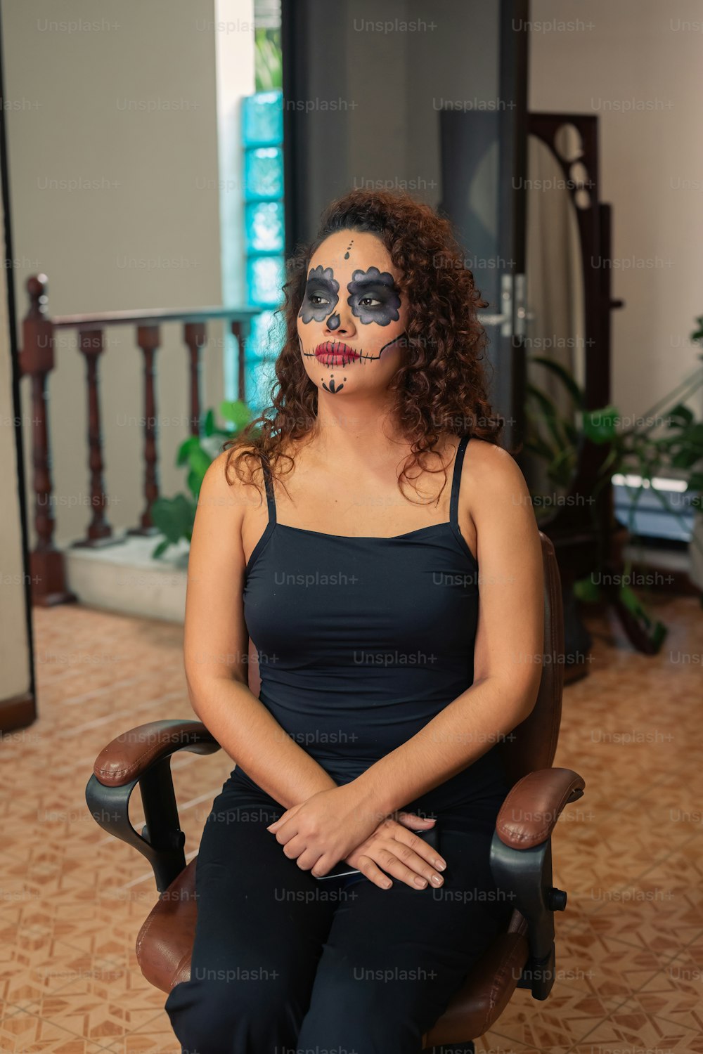 a woman sitting in a chair with her face painted like a skeleton