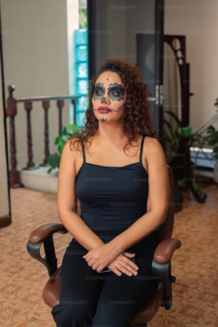 a woman sitting in a chair with her face painted like a skeleton
