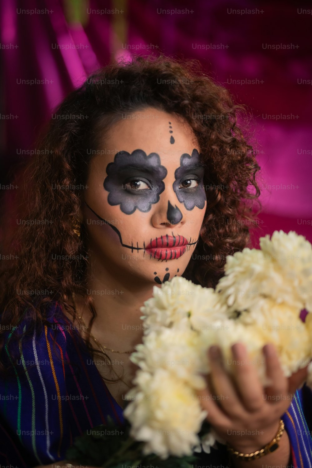 une femme avec de la peinture faciale tenant un bouquet de fleurs
