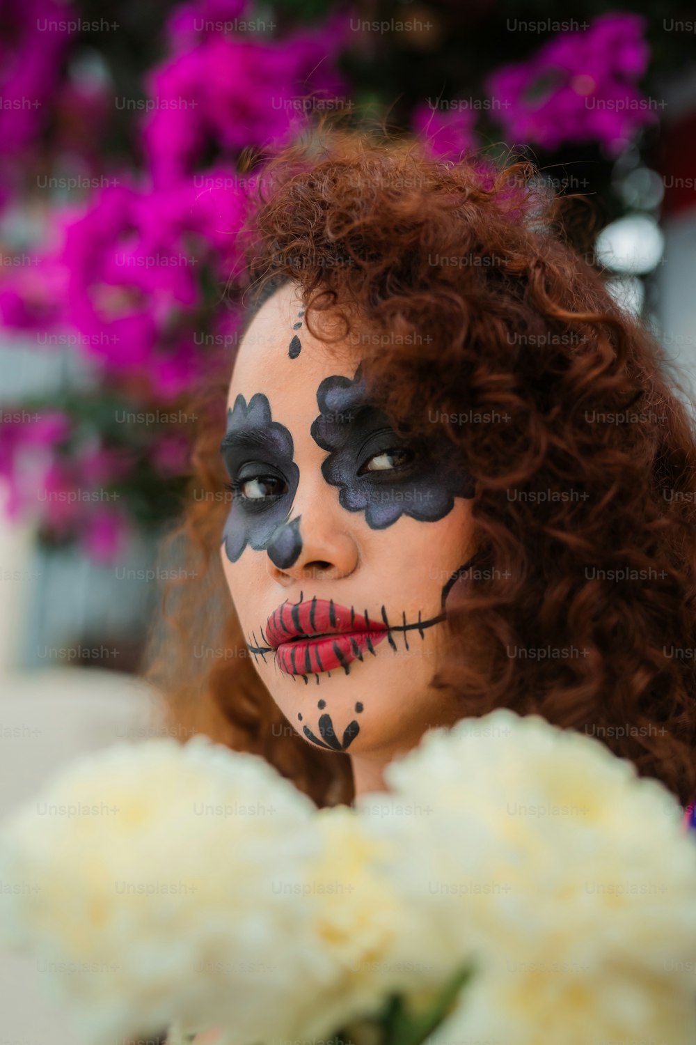 a woman with face paint holding a bouquet of flowers
