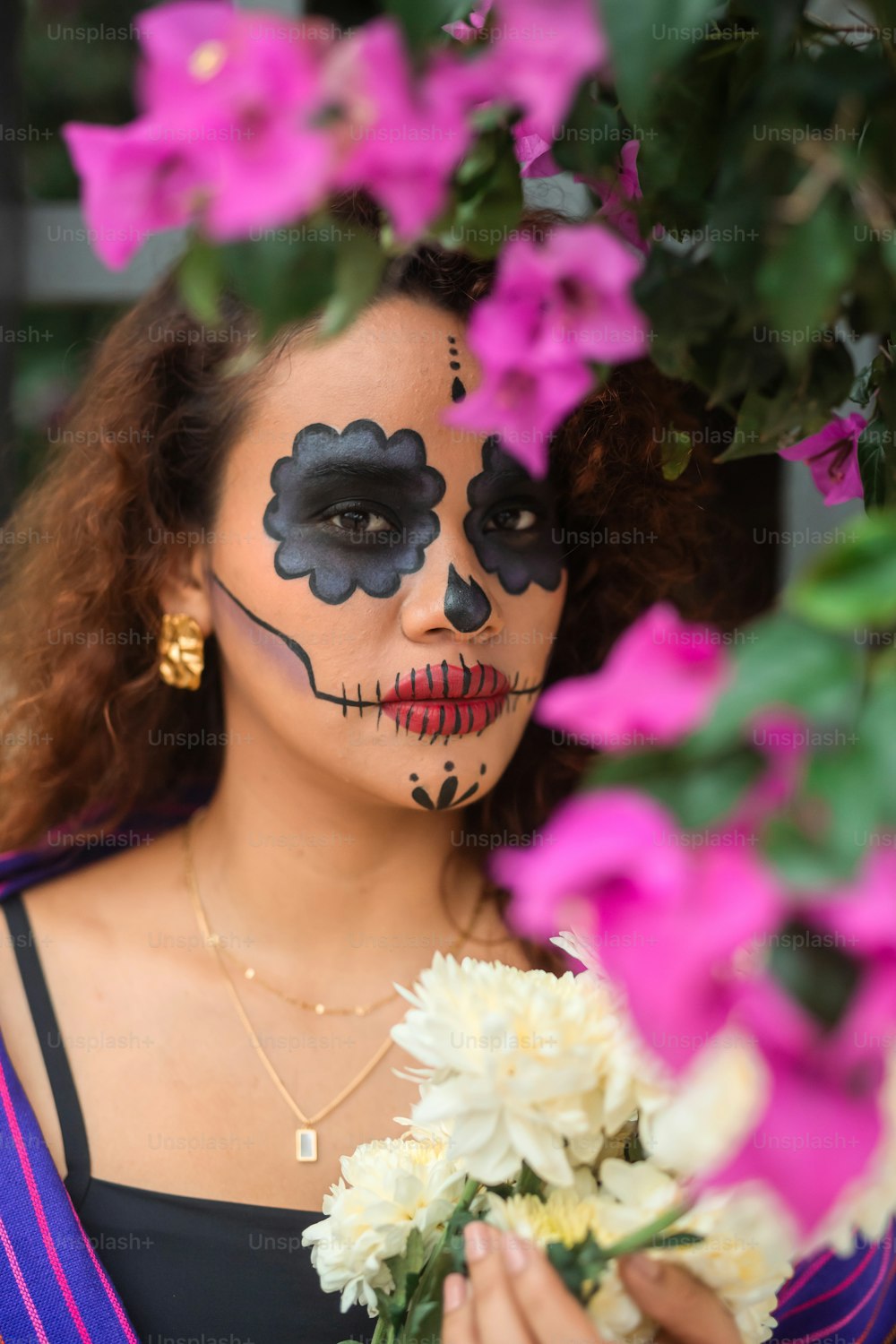 a woman with face paint holding a bouquet of flowers