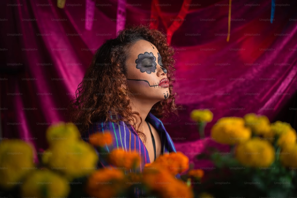a woman with face paint and flowers in front of a curtain
