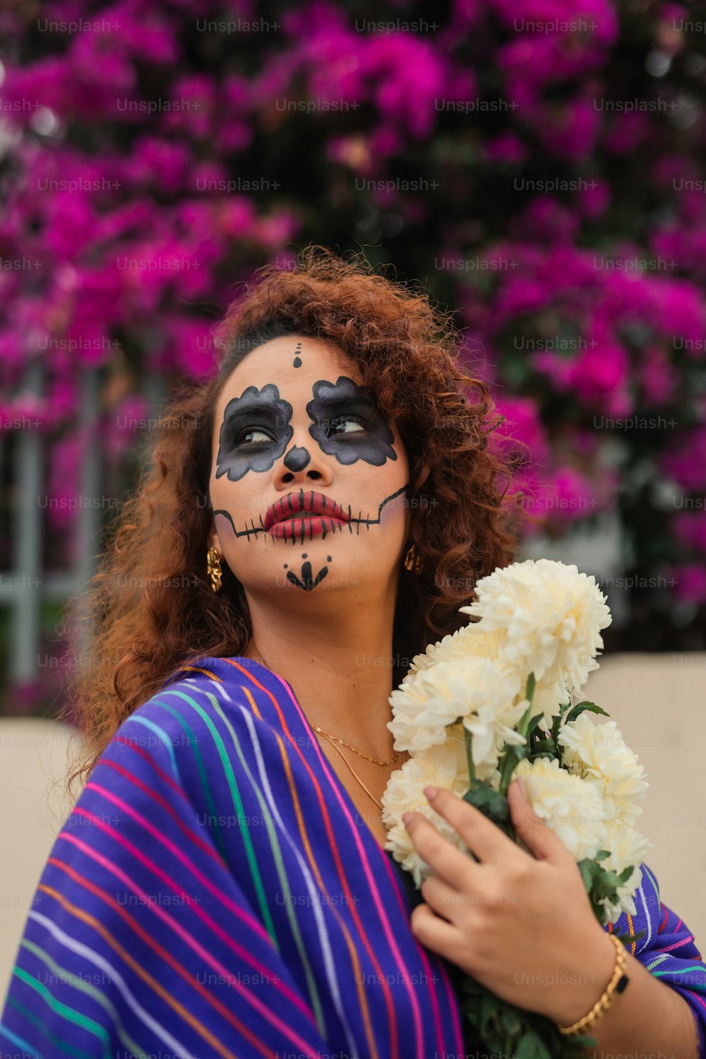 a woman with face paint holding a bouquet of flowers