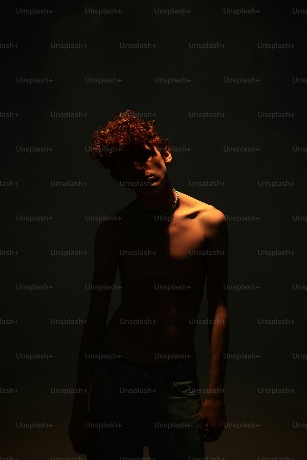Ein Mann ohne Hemd steht im Dunkeln