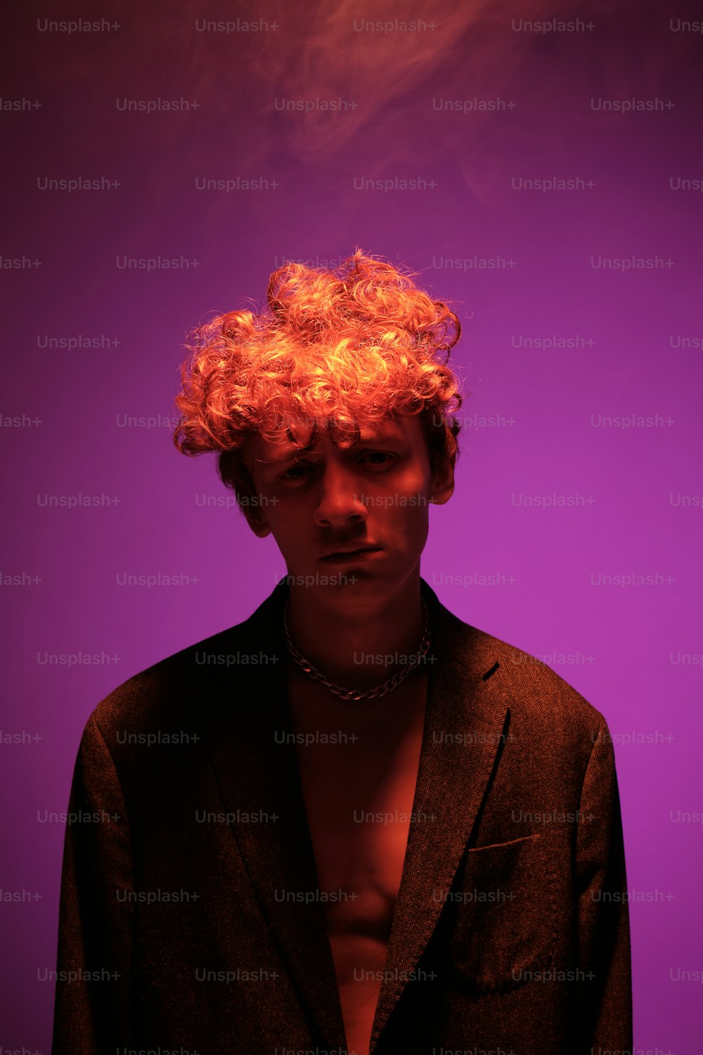 a man with red curly hair standing in front of a purple background