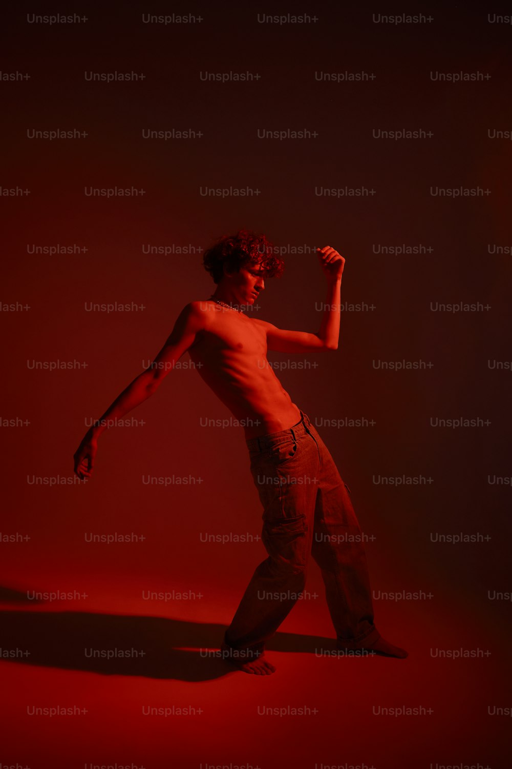 Um homem sem camisa está dançando no escuro