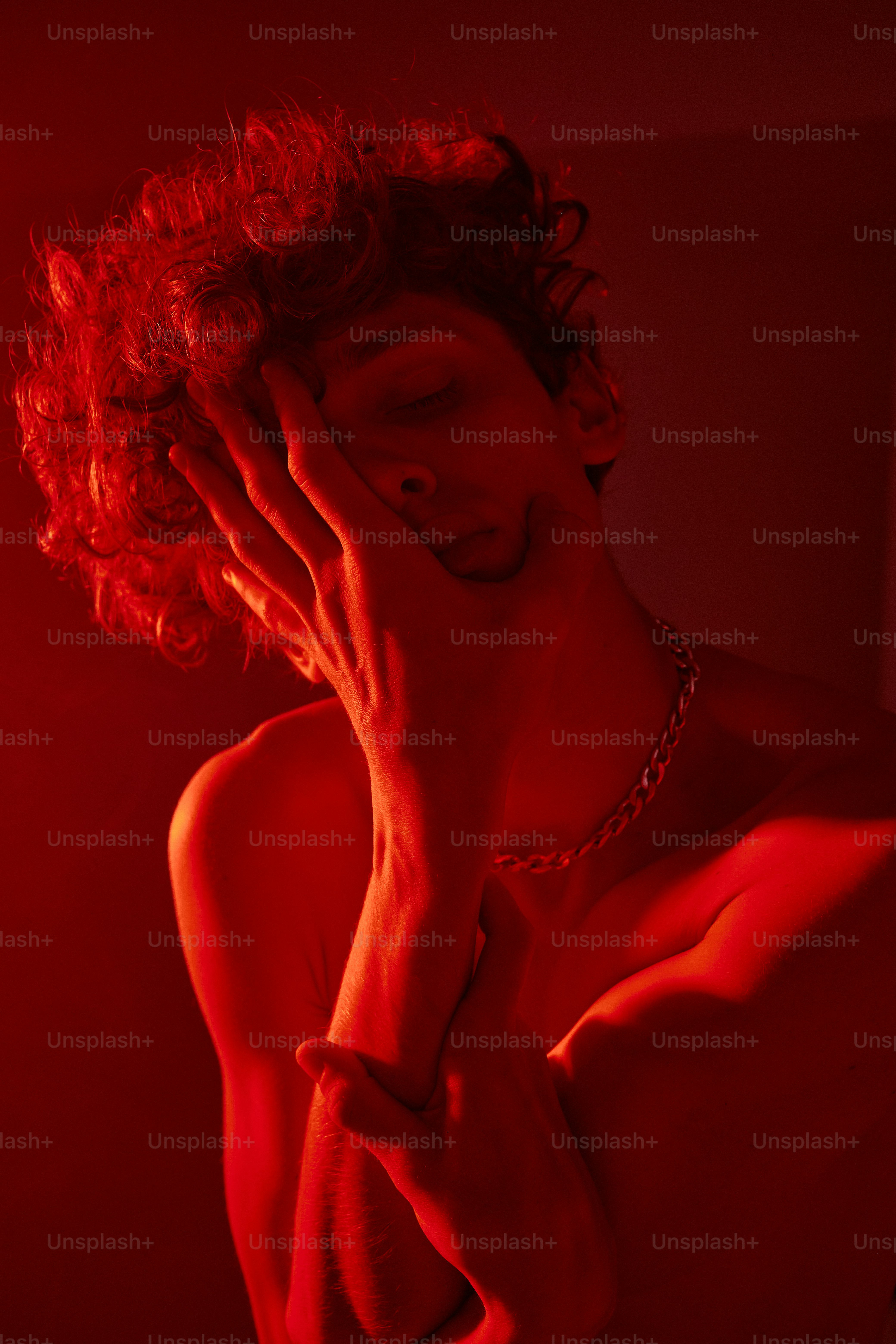 un homme dans une lumière rouge avec ses mains sur son visage