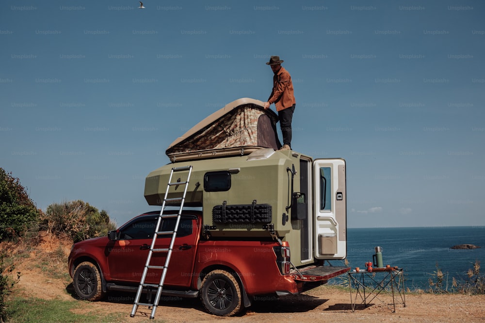 a man standing on top of a truck next to the ocean