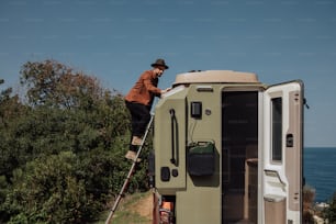 a man standing on a ladder next to a trailer