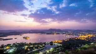 Udaipur city at lake Pichola in the evening, Rajasthan, India. View from  the mountain viewpoint see the whole city reflected on the lake.