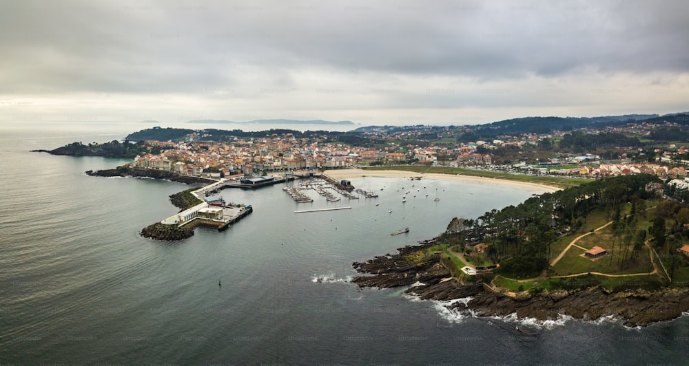 Veduta aerea del faro e del porto di Portonovo, un piccolo villaggio sulla costa della Galizia, in Spagna, con le isole Cies e Ons sullo sfondo.
