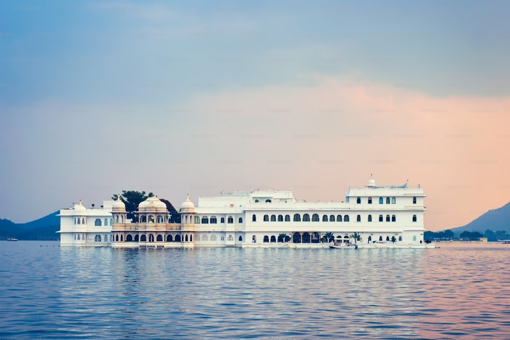 Turismo romántico de lujo en la India - Complejo del palacio del lago (Jag Niwas) en el lago Pichola al atardecer con cielo dramático, Udaipur, Rajasthan, India