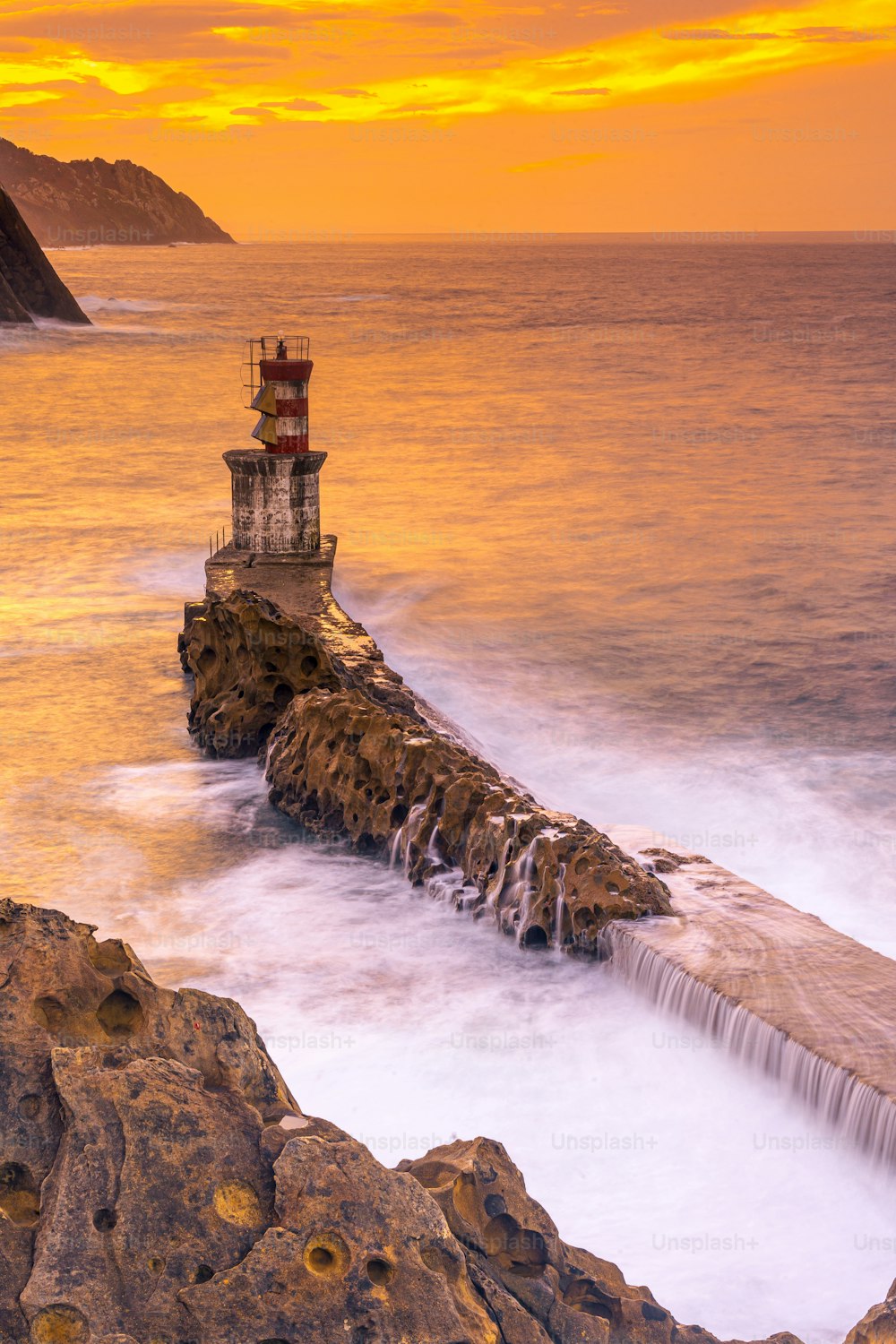 Lunga esposizione al tramonto arancione al faro nel comune di Pasajes San Juan a Gipuzkoa. Province Basche